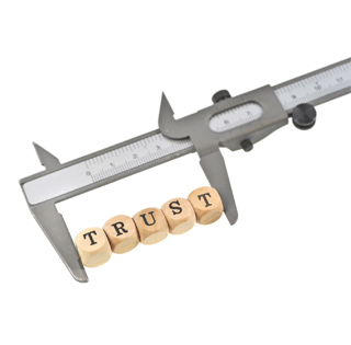 calipers measuring letter blocks that say trust
